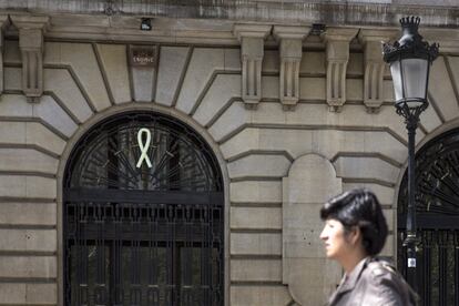 Una mujer pasa frente a la Conselleria de Empresa, que luce a su entrada un lazo amarillo.