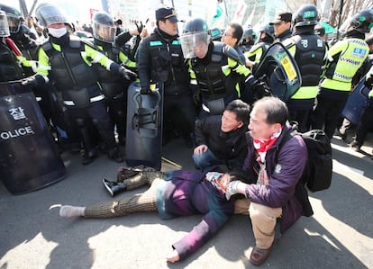 Al menos dos personas han muerto mientras participaban en las manifestaciones multitudinarias en Seúl para protestar por la destitución de la presidenta surcoreana, Park Geun-hye. En la imagen, una mujer permanece tendida en el suelo durante la protesta en Seúl.