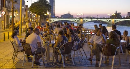 Clientes sentados en veladores de la calle Betis, Sevilla.