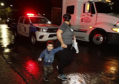 Una mujer y un niño pasan frente a un coche de policía durante el comienzo de la caravana de migrantes en San Pedro Sula (Honduras), el 14 de enero de 2019. Bajo el lema: "En Honduras nos matan", sale desde la catedral de San Pedro Sula, en el norte del país. De no ser exitosa, ya se promueve otra marcha de migrantes que saldría el 20 de enero, desde Santa Bárbara.