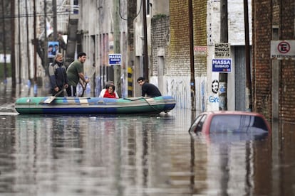 Unos vecinos de Luján se mueven por sus calles inundadas en una lancha.