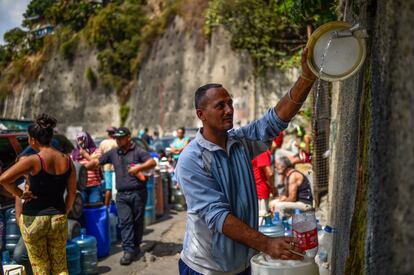 Un hombre llena un recipiente con agua que fluye desde la montaña Waraira Repano, también llamada 'El Avila', en Caracas.