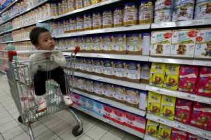 Un bebé espera a su madre en un carrito de la compra en el pasillo de productos lácteos de un supermercado chino. EFE/Archivo