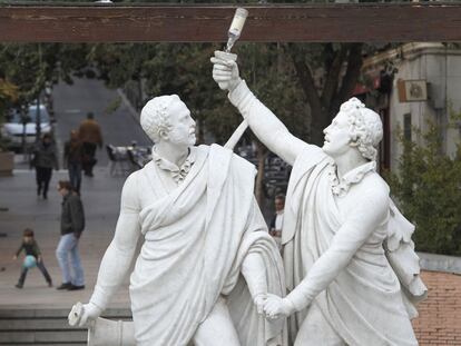 Las esculturas de Daoíz y Velarde, con un botellín en la mano