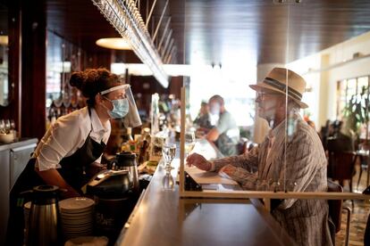 Una camarera habla con un cliente del restaurante Lemeac, el primer día tras el levantamiento de algunas de las restricciones contra el coronavirus, en Montreal (Quebéc, Canadá).