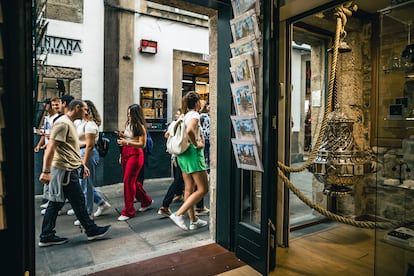 Turistas pasan delante de una entrada de souvenirs de Santiago de Compostela (A Coruña), este miércoles. 