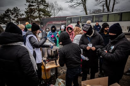 Varios voluntarios ofrecen comida a los refugiados ucranios tras haber cruzado el paso fronterizo entre Rumanía y Ucrania, en Siret (Rumanía). 