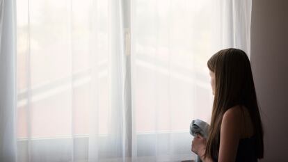 Foto de archivo de una niña mirando por la ventana.