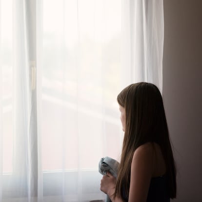 Foto de archivo de una niña mirando por la ventana.