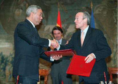 Colin Powell y Josep Piqué se dan la mano, en presencia de Aznar, tras firmar el nuevo convenio.