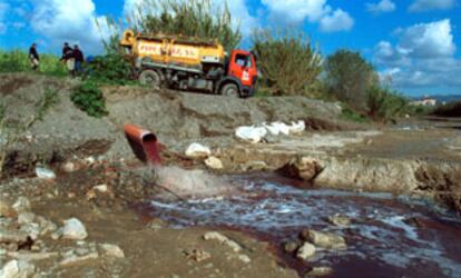 Operarios tratan de reparar el colector para acabar con el vertido al río Campanillas.