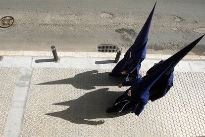 Nazarenos de la hermandad sevillana del Baratillo caminan hacia la capilla para realizar la estación de penitencia.