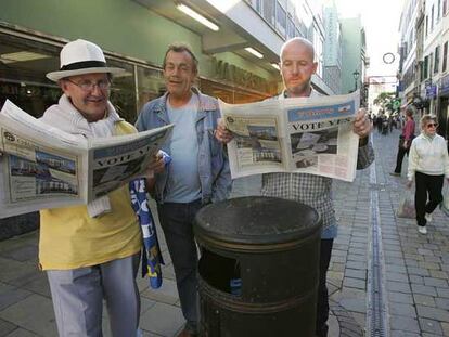 Varios ciudadanos leen en Main Street ejemplares de un diario que pide el <i>sí</i> en el referéndum.