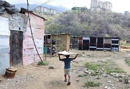 Un niño carga cartón en un terreno ocupado en el municipio de Sucre, cerca de Caracas (Venezuela), el 12 de junio de 2020.