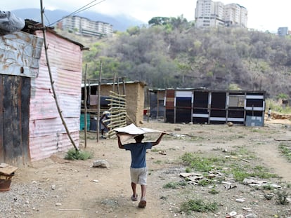 Un niño carga cartón en un terreno ocupado en el municipio de Sucre, cerca de Caracas (Venezuela), el 12 de junio de 2020.