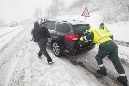 Dos agentes de la guardia civil ayudan a un conductor en un carretera cerca de Pedrafita do Cebreiro (Lugo).