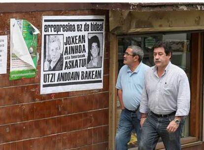 Los concejales Amutxastegi y Vela pasan frente a un cartel de apoyo a Barandiaran y Ozaeta.