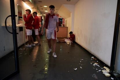 Varios jóvenes reponen fuerzas en una tienda de bocadillos durante la tarde del primer día de San Fermín 2022.