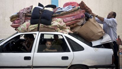 Um homem coloca seus pertences no teto do carro para retornar para sua casa com a família, depois de terem permanecido refugiados em uma escola da ONU.