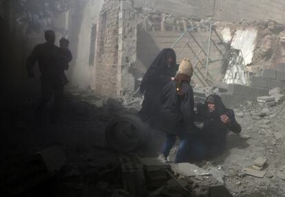 Una mujer siria es ayudada a levantarse durante la huida de los bombardeos, el 8 de febrero de 2018. De acuerdo con el Observatorio Sirio para los Derechos Humanos, desde el pasado 29 de diciembre han muerto en los bombardeos sobre Ghuta Oriental al menos 427 personas, entre ellas 105 niños.