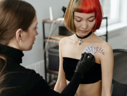 Una tatuadora retirando el papel que sirve posteriormente de guía para realizar el tatuaje