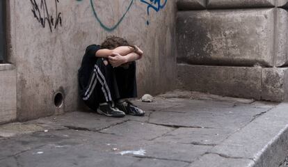 Un niño acurrucado en una calle.