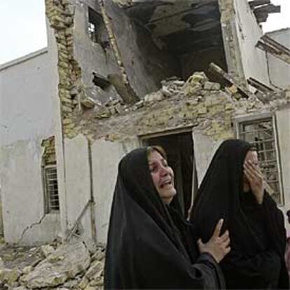Dos mujeres lloran ante una vivienda que resultó destrozada en el atentado de ayer en Hilla.