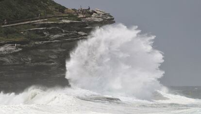 La gente observa una gran ola golpeando la costa de la playa de Tamarama, en Sydney (Australia).