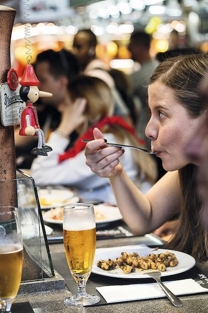 Una clienta come una ración de garbanzos con morcilla en el Pinotxo Bar, en el Mercado de la Boquería de Barcelona.