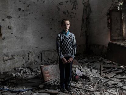 Yura Khromchenko, de nueve años, posa en un aula de infantil destruida por una bomba el pasado septiembre en la región de Luhansk (Ucrania).