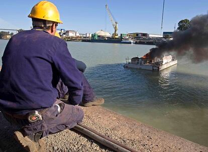 Trabajadores de astilleros de Sevilla durante la protesta en el río Guadalquivir con una barcaza llena de contenedores de material inflamable.