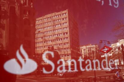Unos edificios se reflejan en un cartel de una oficina del Banco Santander en Madrid
