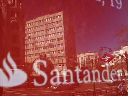 Unos edificios se reflejan en un cartel de una oficina del Banco Santander en Madrid