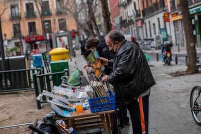 Un vendedor ambulante con mascarilla clasifica vinilos.