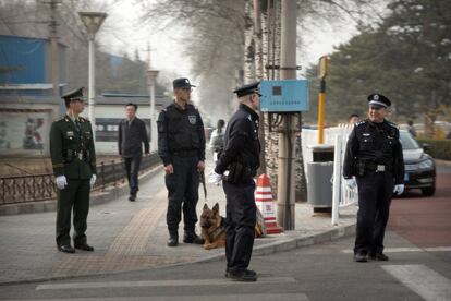Policías y oficiales de seguridad chinos vigilan una calle cerca a la residencia para huéspedes en Pekín.