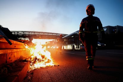 Un agente de policía camina junto a una hoguera mientras despejan una autopista, durante una protesta del movimiento 'Bloqueemos todo' en Porte d’Aubervilliers, París.