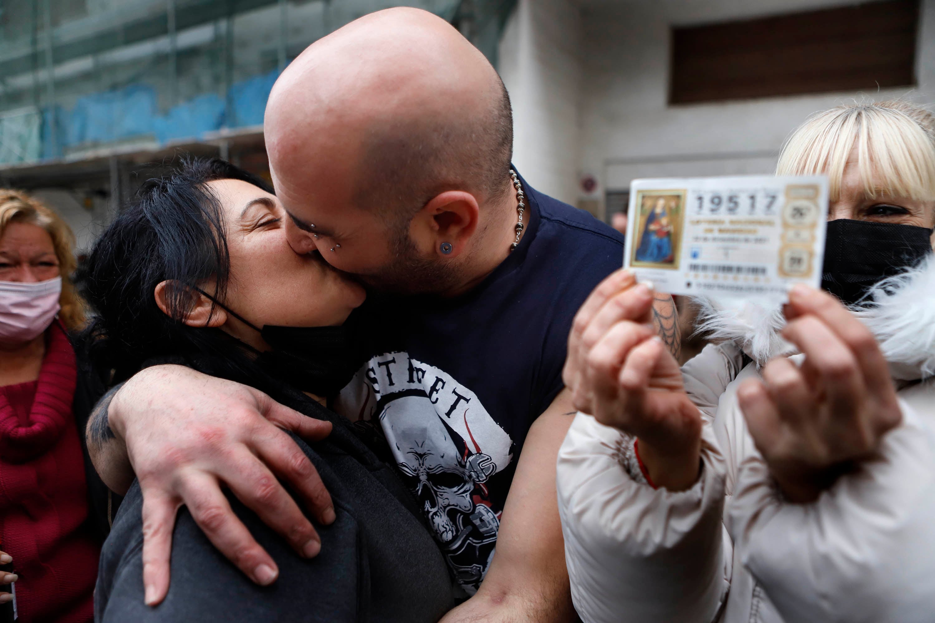 Cárol Pérez y Tino Santamarta se besan junto a una clienta que muestra el décimo premiado