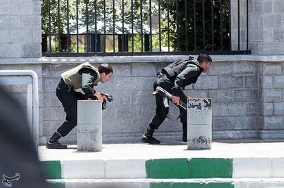 Miembros de las fuerzas iraquíes se cubren durante el ataque al parlamento iraní.