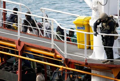 Un soldado y un grupo de migrantes esperan en el barco al llegar a Malta.