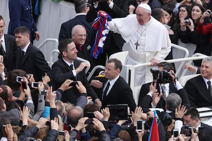 El Papa Francisco recoge una camiseta de su equipo lanzada por el público en la plaza de San Pedro.