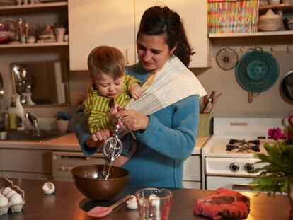 Una mujer cocina con su bebé en brazos.