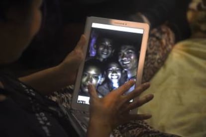 Familiares observan a través de un dispositivo electrónico a los niños atrapados en una cueva en Tailandia.