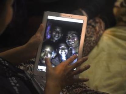 Familiares observan a través de un dispositivo electrónico a los niños atrapados en una cueva en Tailandia.