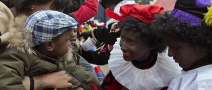 Un niño asiste a la cabalgata de San Nicolás con los pajes negros en Ámsterdam.