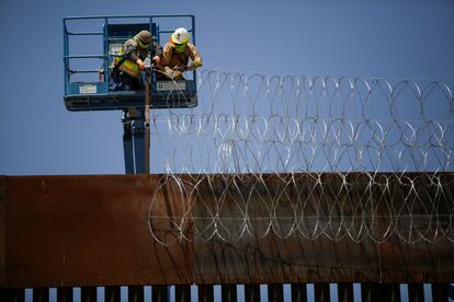 Dos operarios colocan una concertina sobre la valla fronteriza que separa Texas (EEUU) de Ciudad Juárez (México).