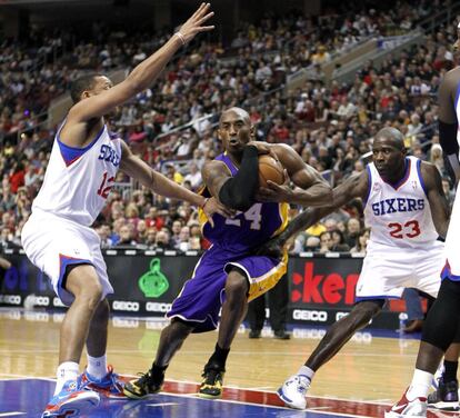 Bryant abraza el balón con fuerza mientras va hacia canasta entre Evan Turner y Jason Richardson.