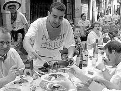 Los miembros de una peña, almuerzan en la calle san Antón, después de pasar la procesión de san Fermín.