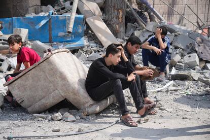 Varios jóvenes palestinos, sentados en las ruinas de un edificio bombardeado en el campo de refugiados de Nuseirat, en la franja de Gaza.