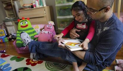 Christopher Astacio lee con su hija, Cristina de dos años, diagnosticada de autismo. / Bebeto Matthews
