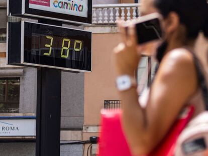 Una mujer pasa en Mallorca junto a un termómetro que muestra la temperatura en grados Celsius, el pasado agosto.